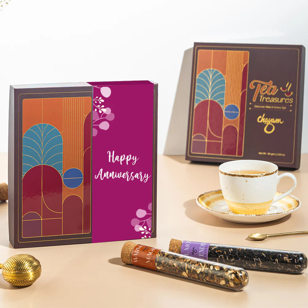 Chayam Tea Treasure packaging with 'Happy Anniversary' message, tea cups, and tea sticks on a table for anniversary gifting.