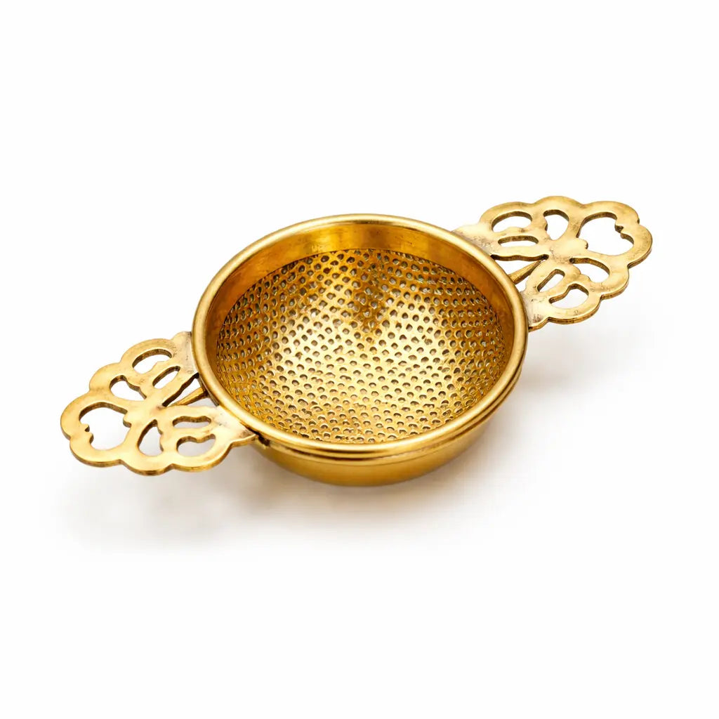 Brass decorative strainer on a white background