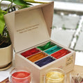 Chayam assorted tea gift box open, showing 48 colourful pyramid tea bags, with cups of tea alongside